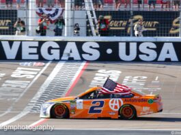 Brad Keselowski does his traditional victory celebration with the American flag. He also celebrated Team Penske's 500th career victory. Photo by Rachel Myers for Speedway Media.