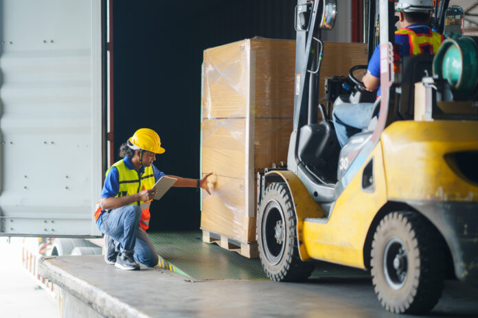 forklift driver loading a shipping cargo container with a