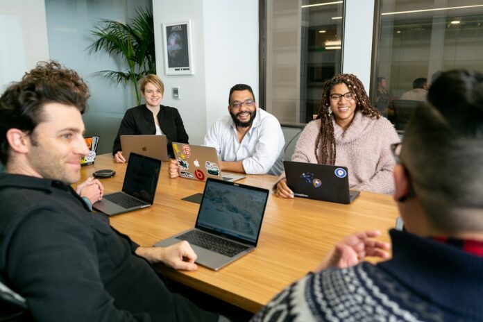 A team of workers collaborating around a table, discussing project plans and resource utilization strategies.