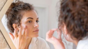woman looking in mirror and doing beauty face routine