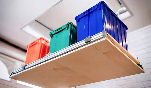 3 Essential Garage Upgrades Racing Fans Crave Overhead garage storage lift holding colorful plastic containers
