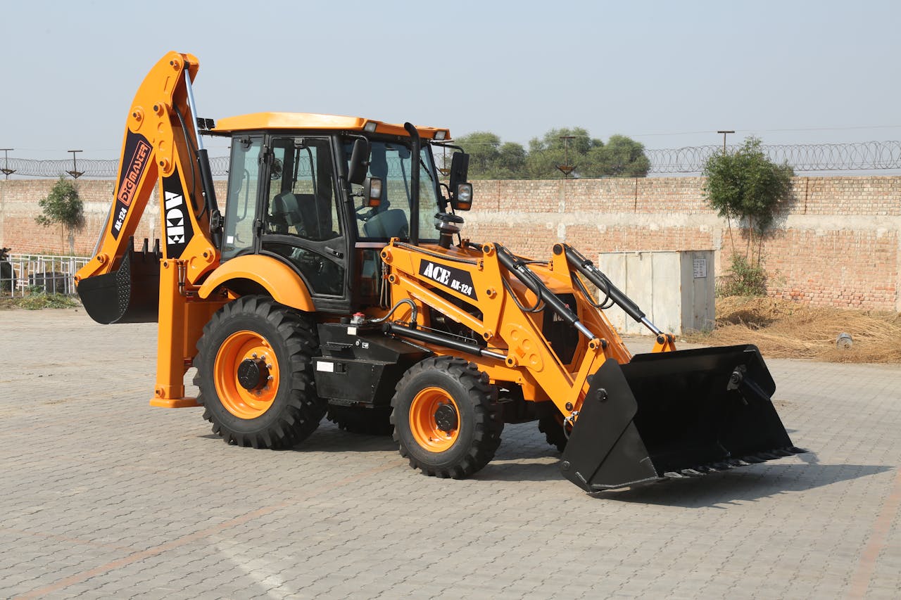 3 Ways Heavy Equipment Keeps Racetracks Ready for Race Day Yellow ACE backhoe loader parked on a paved lot